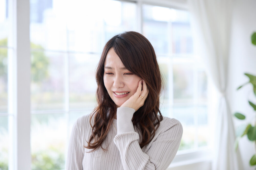 歯が欠けた・折れた・ヒビが入ったことで頬を押さえて痛みを感じる女性